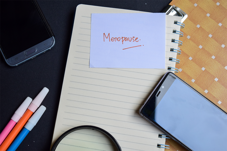 Work desk with 'menopause' note stuck on the front of a file